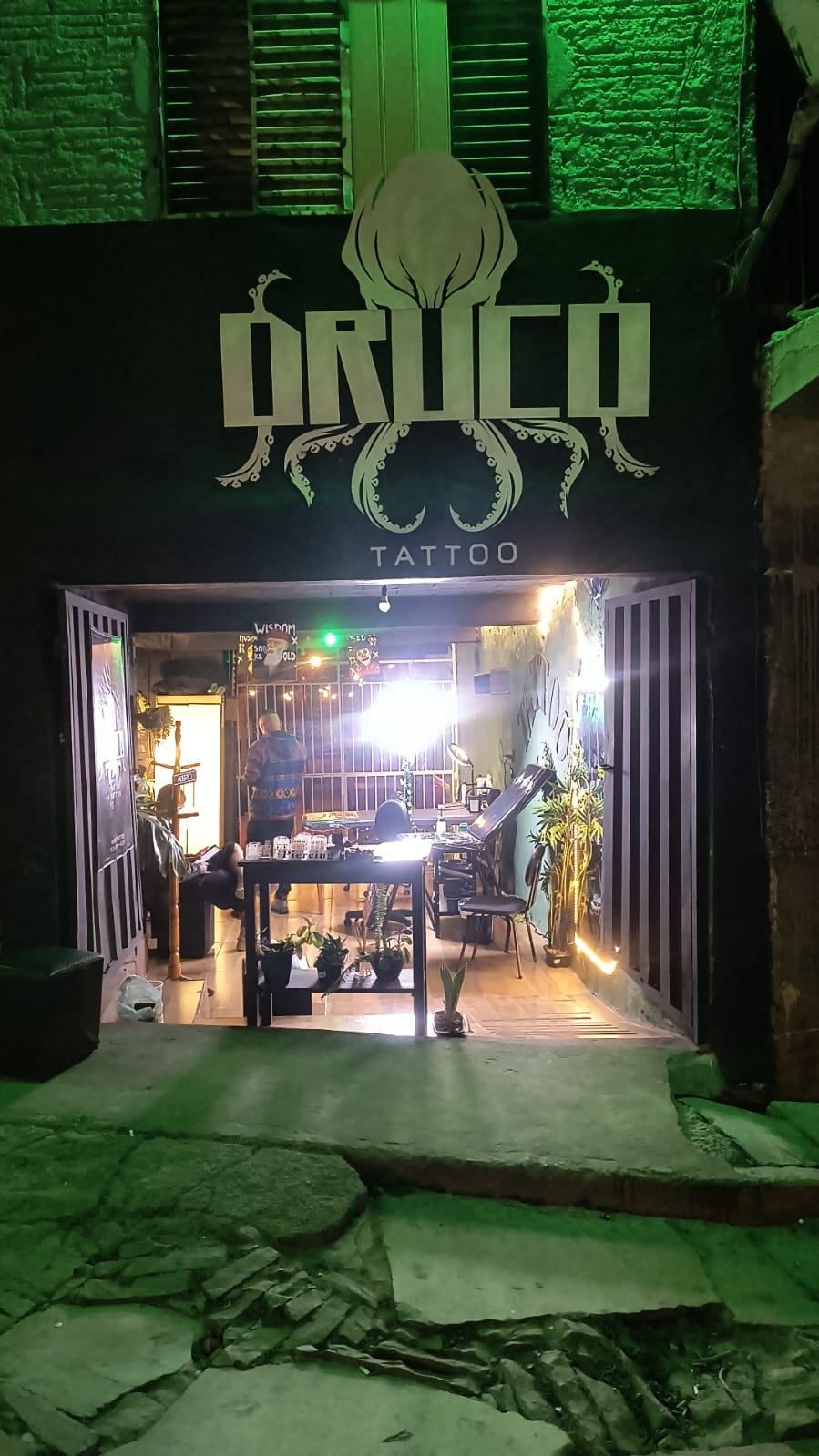 Entrada do estúdio Druco Tattoo iluminada à noite em São Tomé das Letras